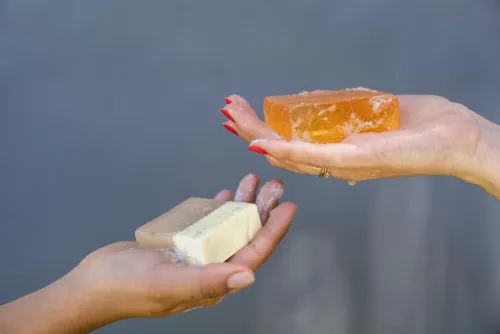 Two hands holding two bars of soap