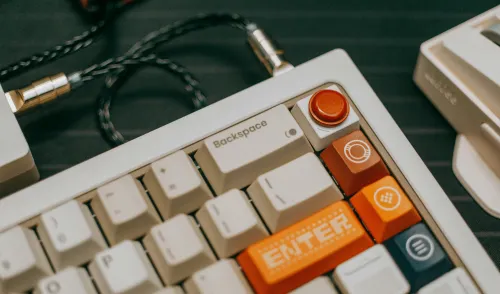 White mechanical keyboard with custom keys and a headphone cable plugged into the top