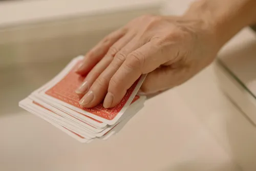 Person taking a red playing card from a deck on the table