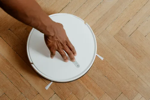 Person turning on a floor robot vacuum