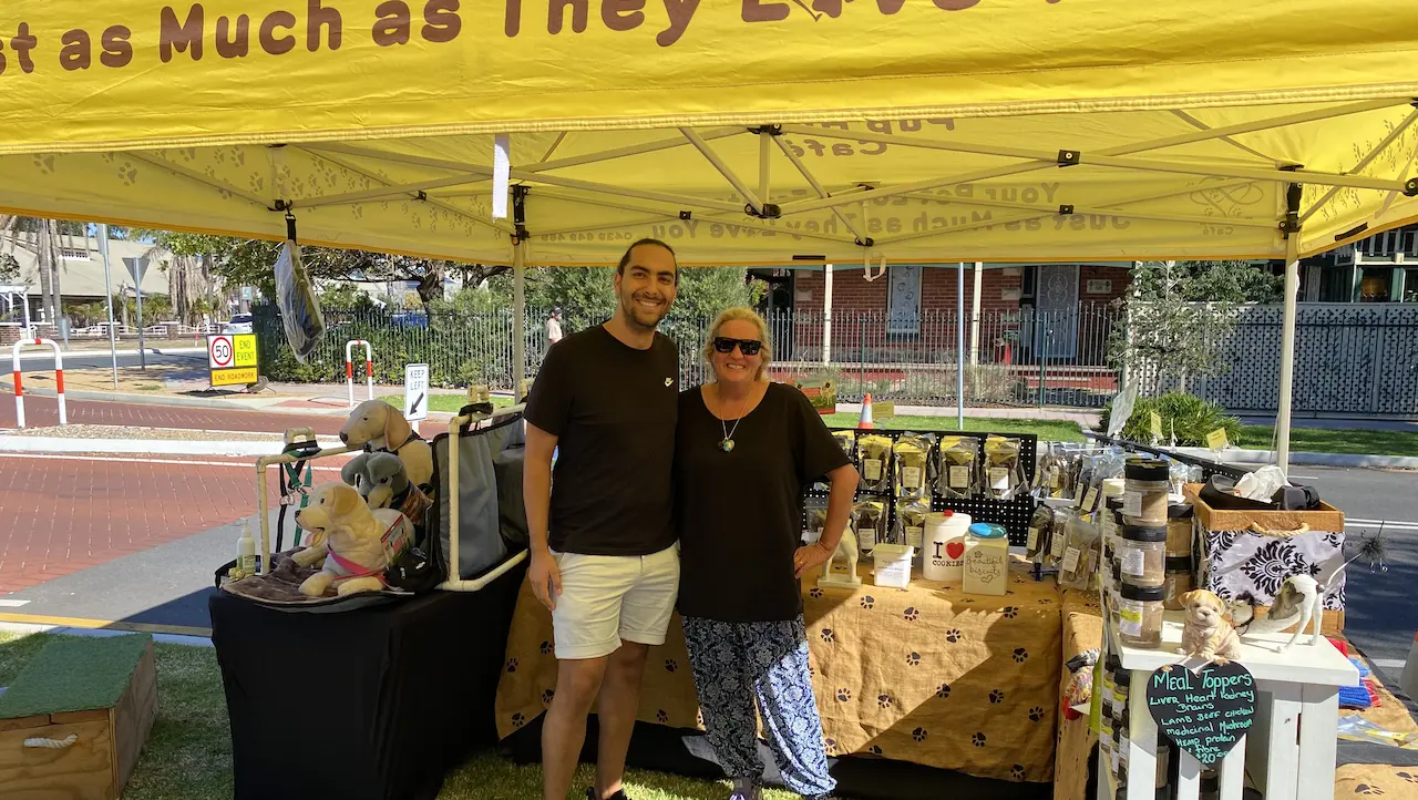 Dom Tripodi and Jo Rugless at a local market in Adelaide at the front of a tent for the Pup Hub Cafe.